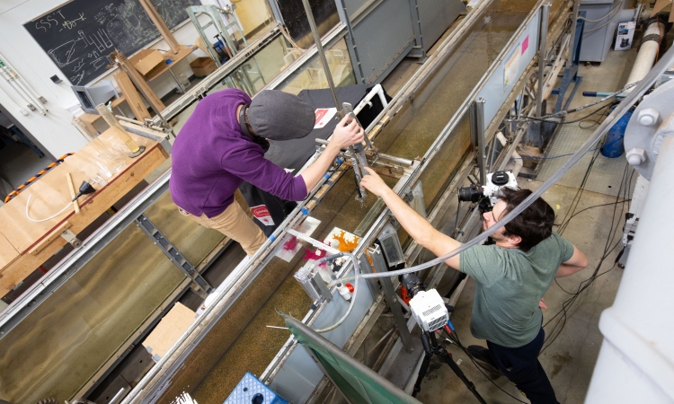 Two people set up a camera above a flume 