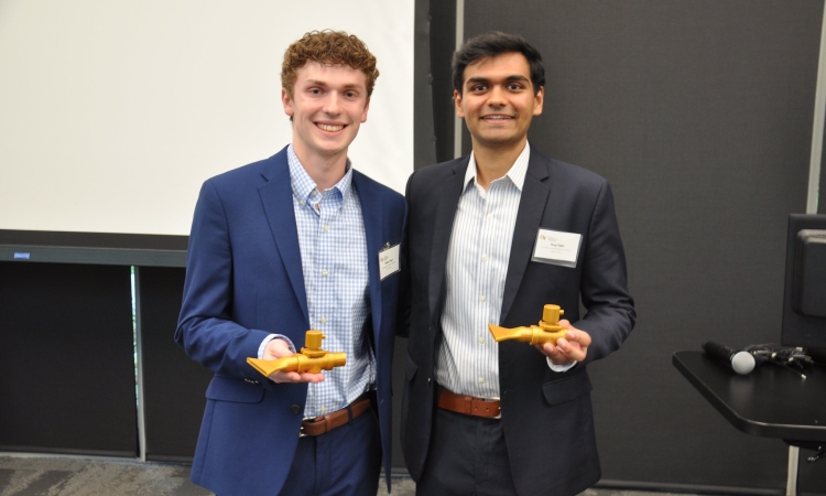 Two men pose holding gold 3-D printed prototypes