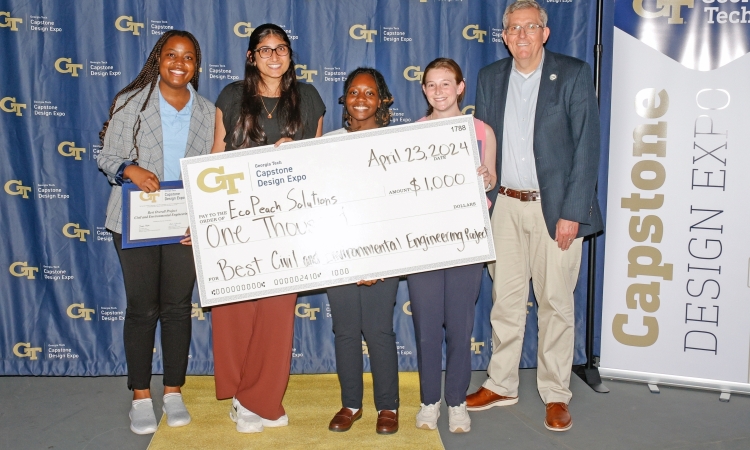 The EcoPeach Solutions Team poses with an oversized check