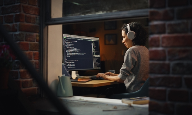 A woman wearing headphones sitting in front of a computer screen