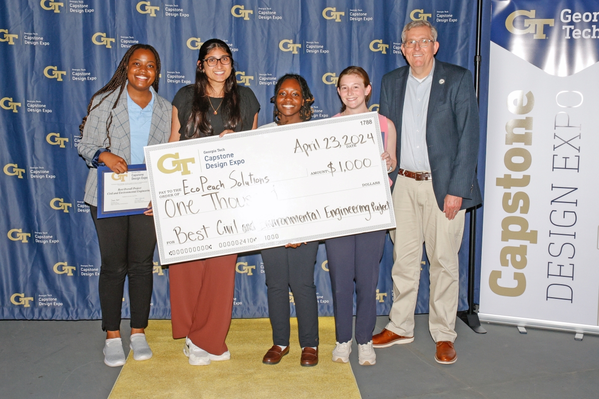 The EcoPeach Solutions team poses with an oversized check