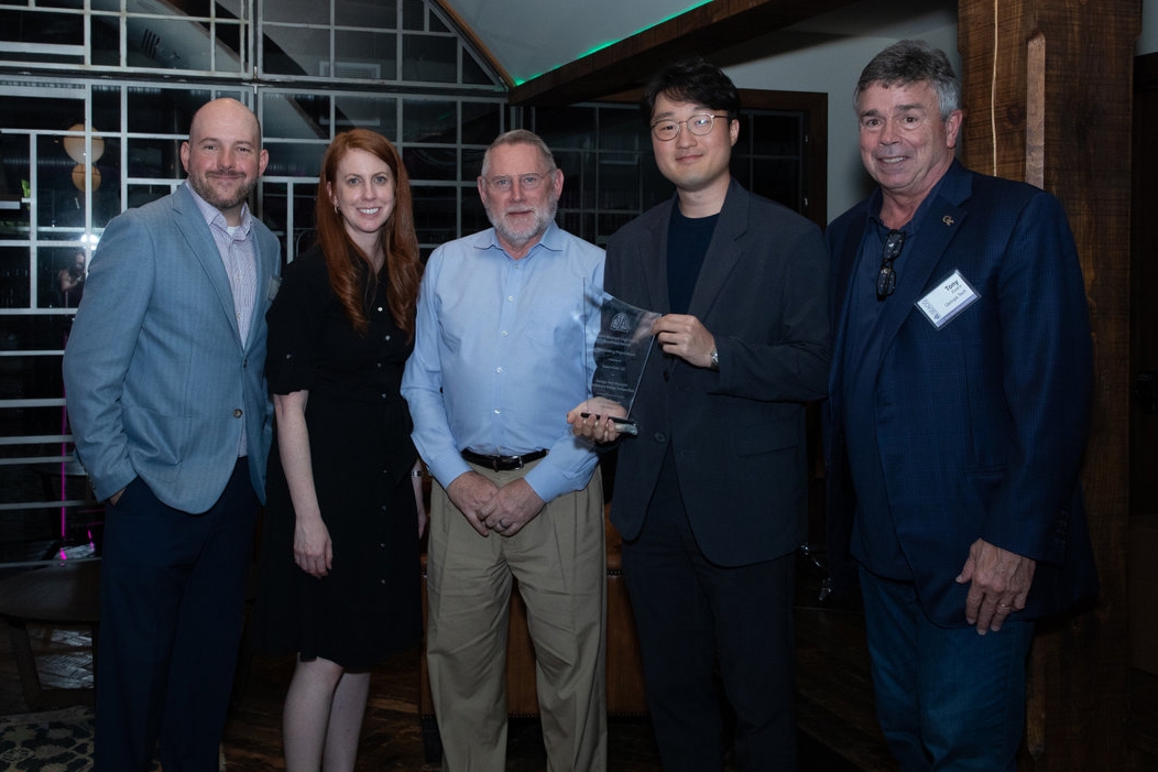 Five people pose with a glass award