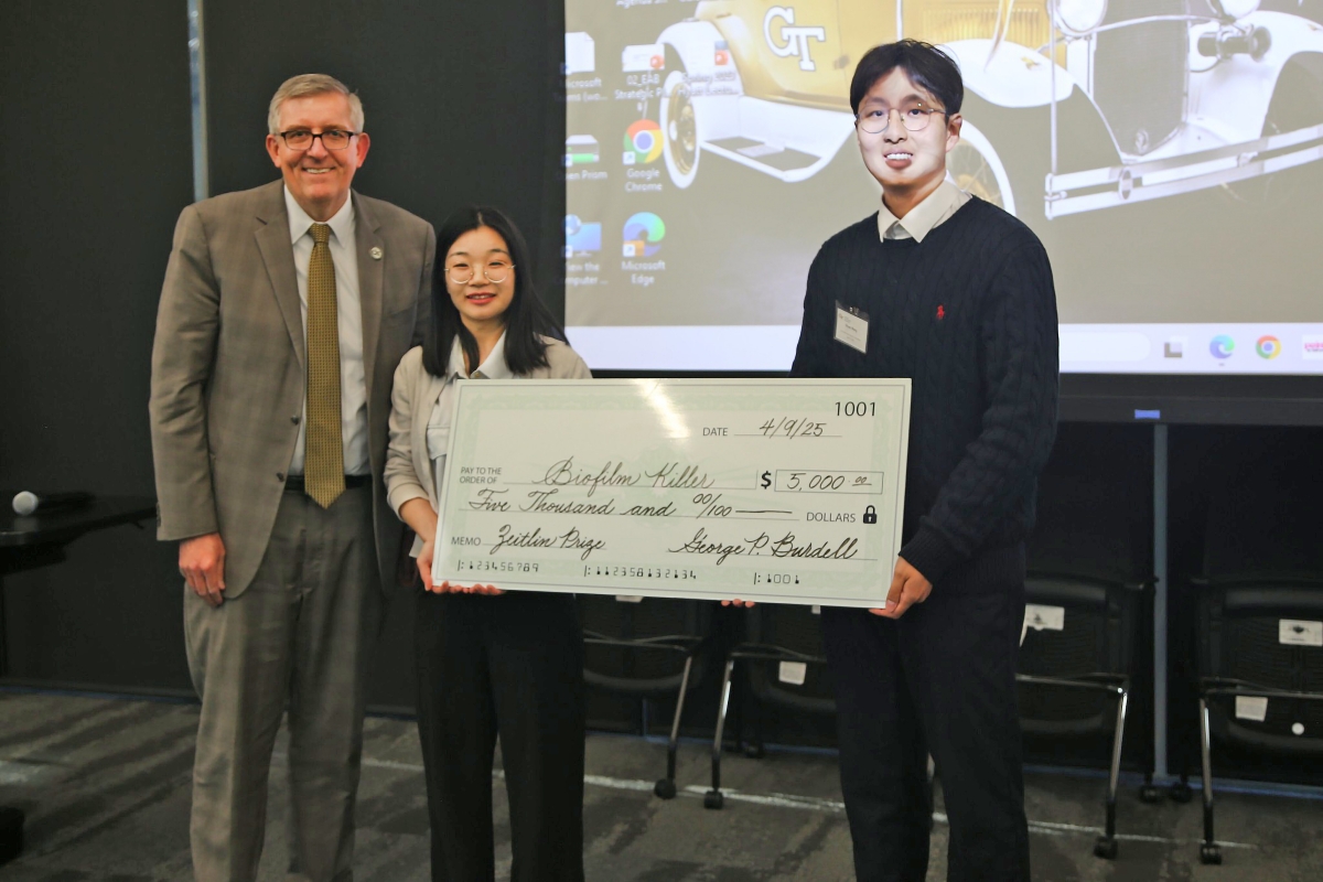 Karen and John Huff School Chair Don Webster presents the Biofilm Killer team, FeiFei Liu and Shuai Wang with a big green check.