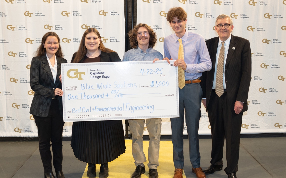 Photo of four students of Blue Whale Solutions team holding big check with Chair Don Webster