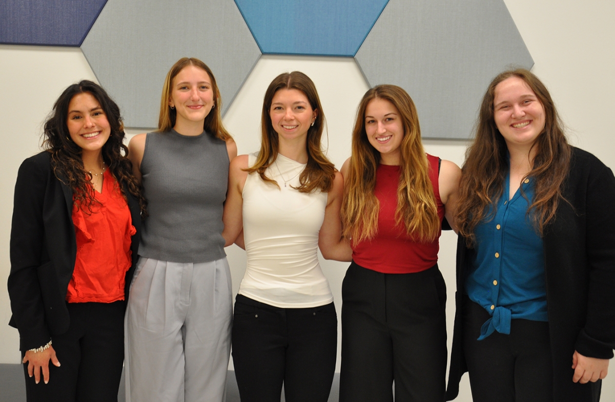 Five women in front of blue hexagon tiles