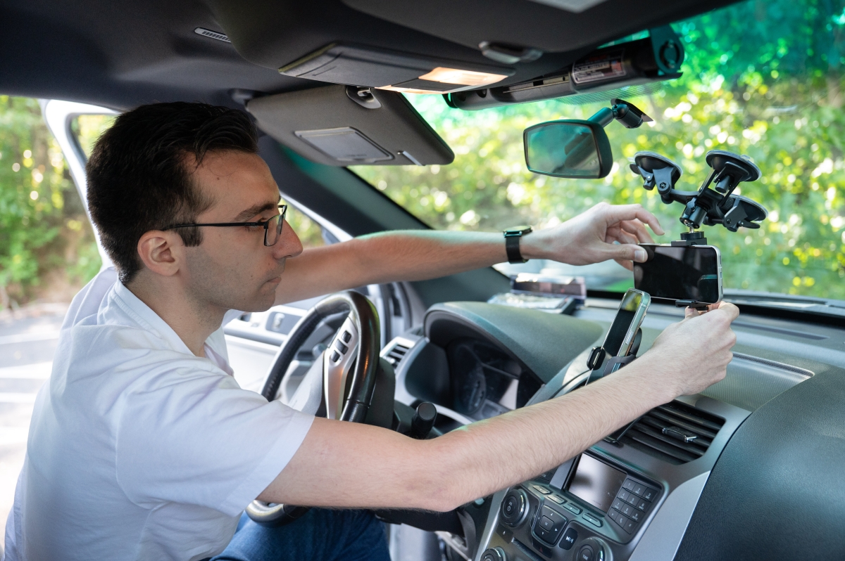 A man mounts a smart phone onto a windshield