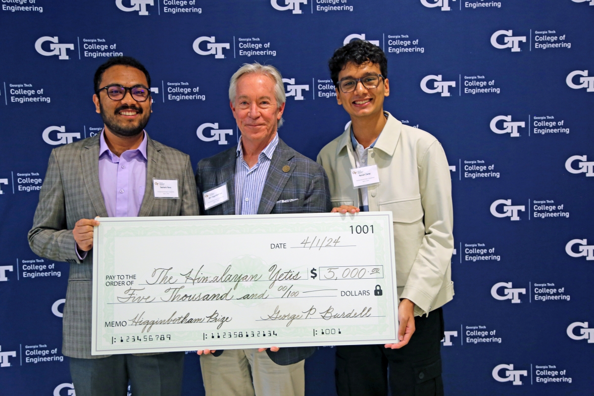 Two students from the 2024 Higginbotham Prize winning team Himalayan Yetis pose with Bill Higginbotham and a giant check