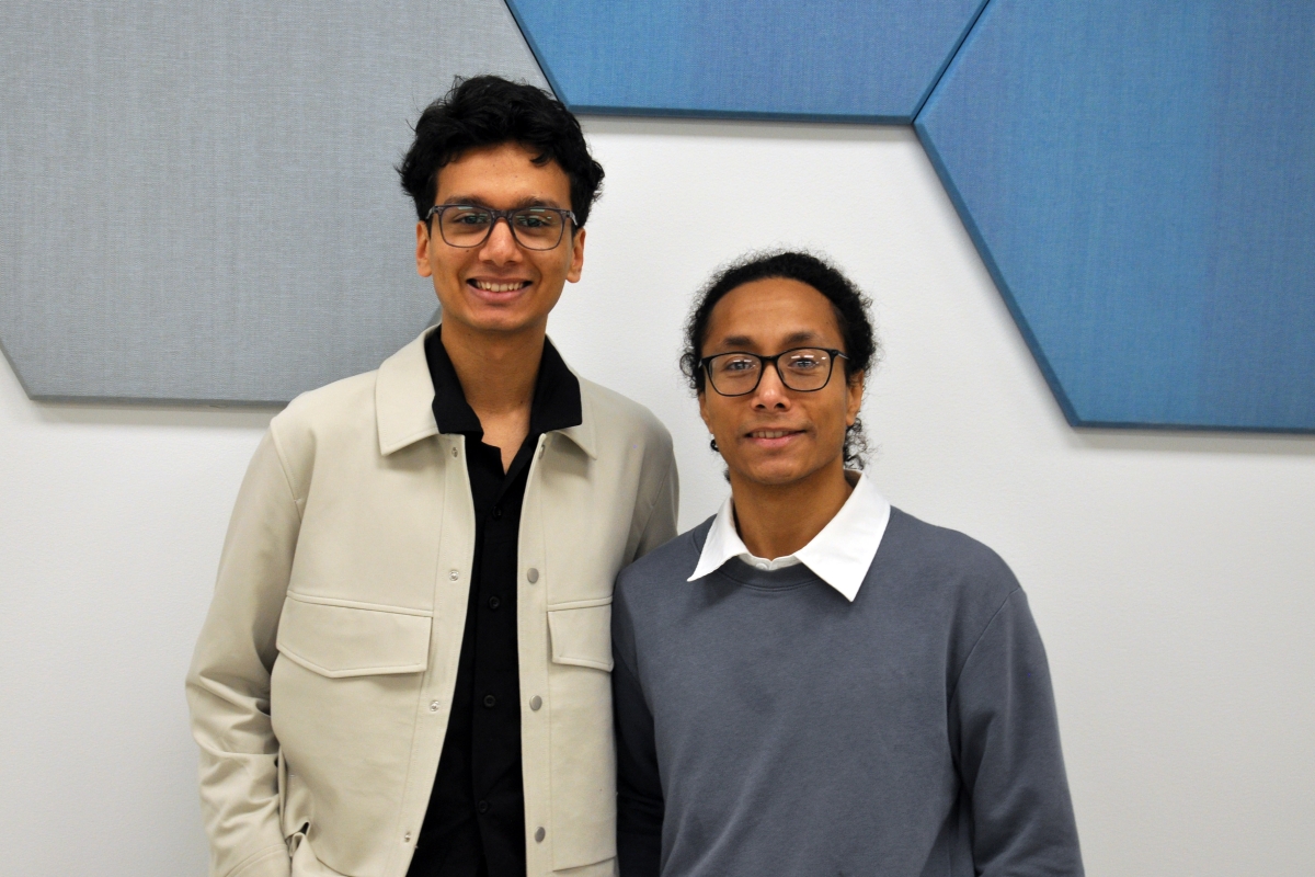 Two people standing in front of blue hexagonal tiles 