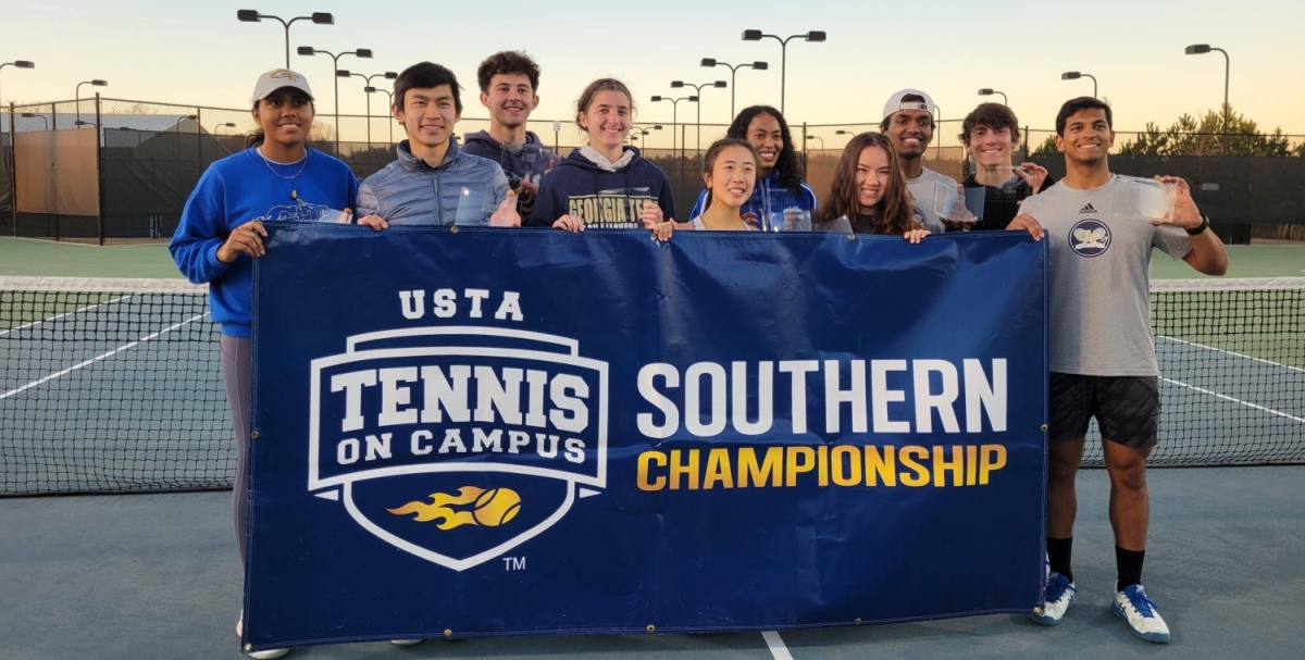 A group of people poses behind a banner that said USTA Tennis on Campus Southern Championship 