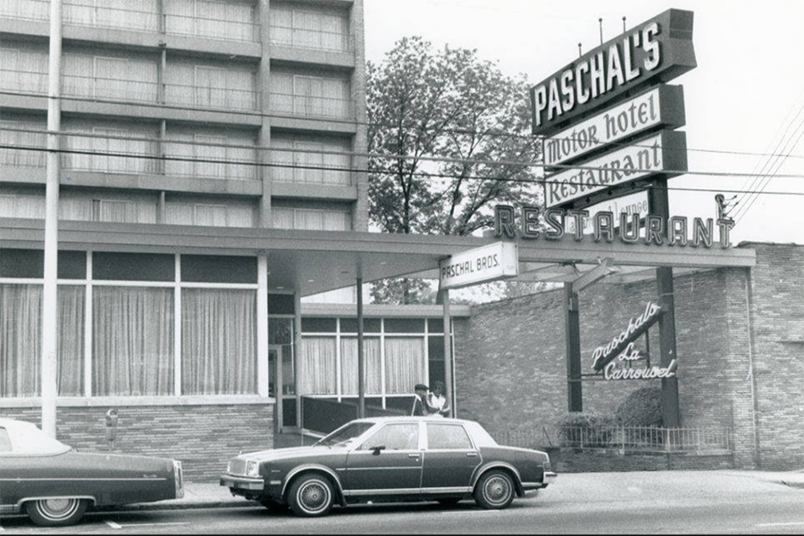 A black and white vintage photo of cars parked in front of the marquee sign for Paschal's Motor Hotel and Restaurant