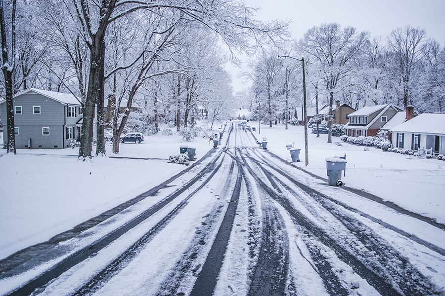A snowy residential street with gray skies