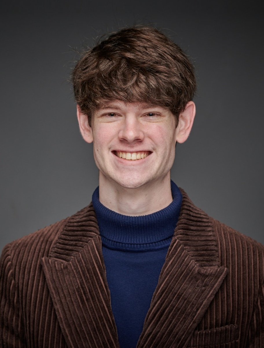 Jackson Stewart wearing a blue turtleneck and a brown corduroy blazer