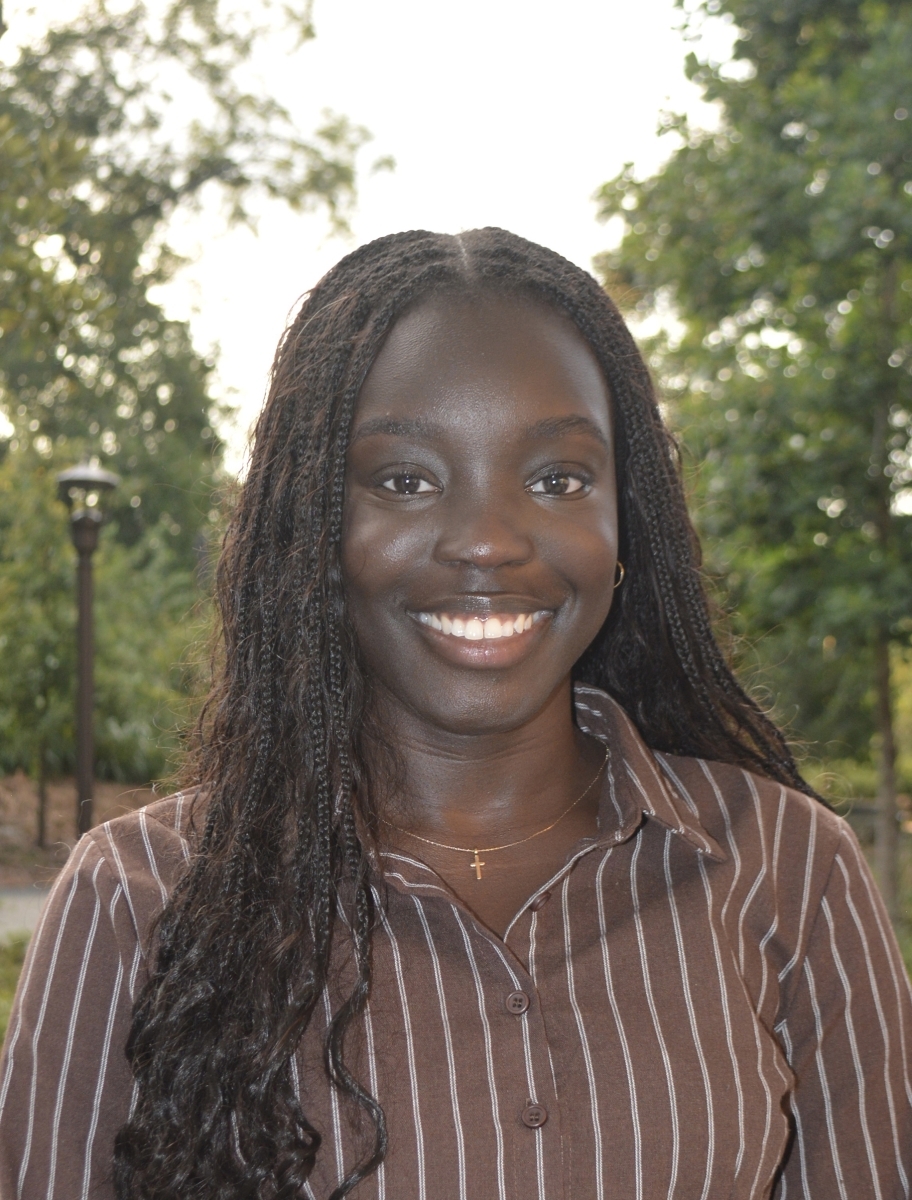 Portrait of Lavine Chuol in a brown shirt with white stripes