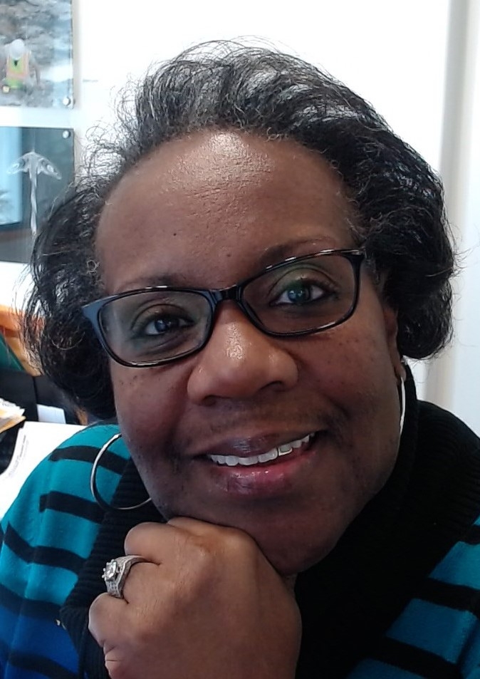 Portrait of LaShone Simmons in glasses, big hoop earrings and a blue striped sweater