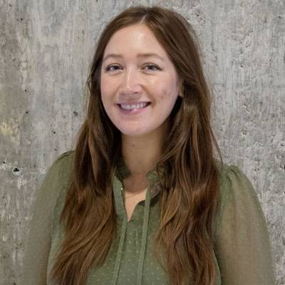Portrait of Dr. Katherine Graham in a green blouse against a concrete wall background