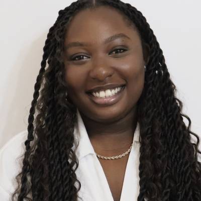 Portrait of Kathryn Owusu in a white blouse with a gold necklace