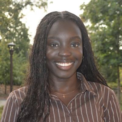 Portrait of Lavine Chuol in a brown shirt with white stripes
